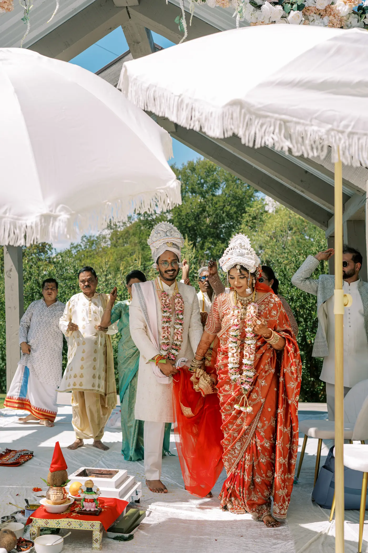 Bengali bride and groom in traditional headpieces during a havan ceremony in the covered pavilion at The Penrose House