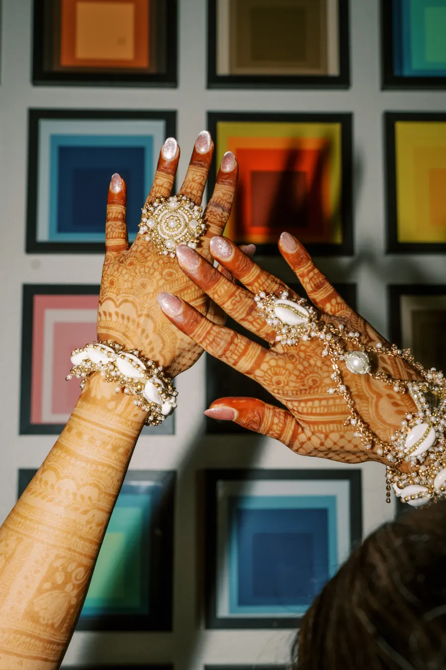 Bridal mehndi hands with pearl haath phool jewelry against a colorful art wall at The Penrose House