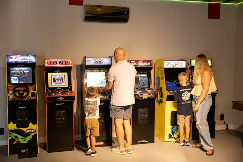 Family playing classic arcade games in the game room at The Penrose House