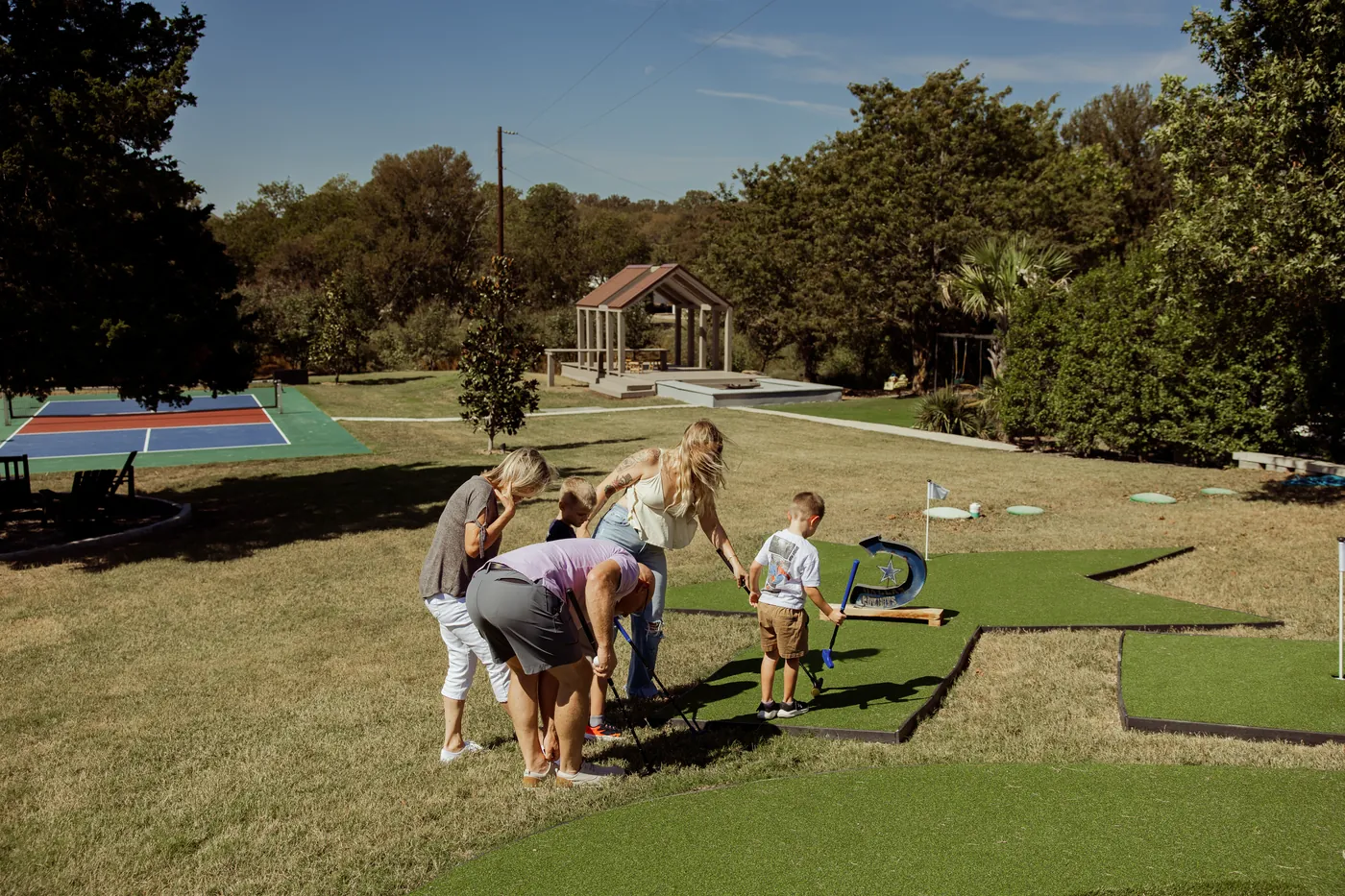 Family playing mini golf on the lawn by the pickleball court at The Penrose House