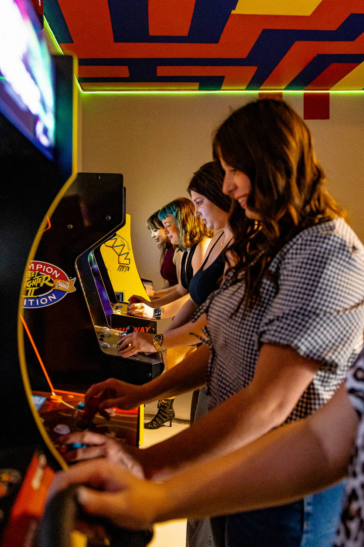 Friends playing arcade games in the Plus One Lounge, The Penrose House