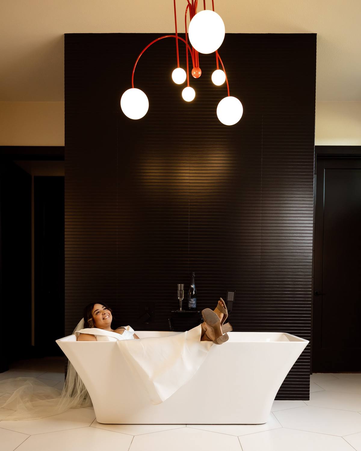 Bride relaxing in a freestanding tub with champagne, The Penrose House
