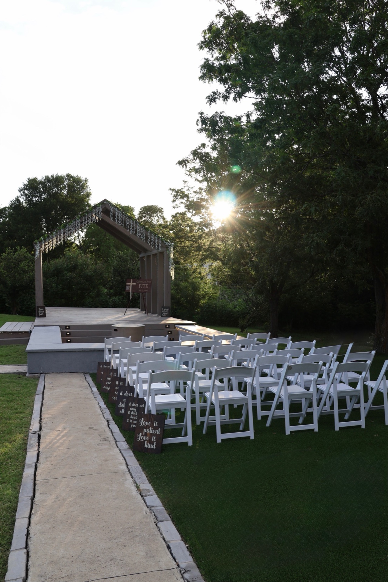 Covered chapel stage at sunset with wooden 'Love is Patient' scripture signs lining the aisle