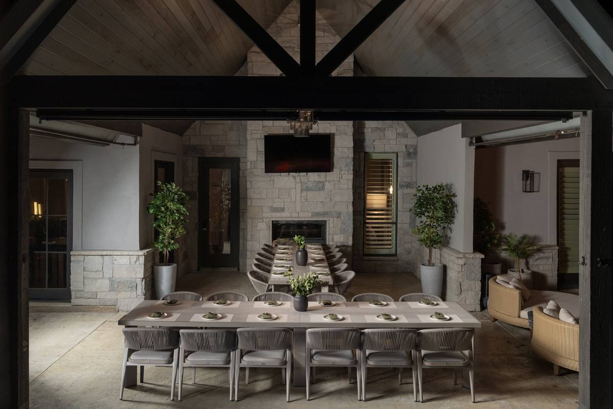 Covered outdoor dining pavilion with a stone fireplace and a long table set for dinner, The Penrose House