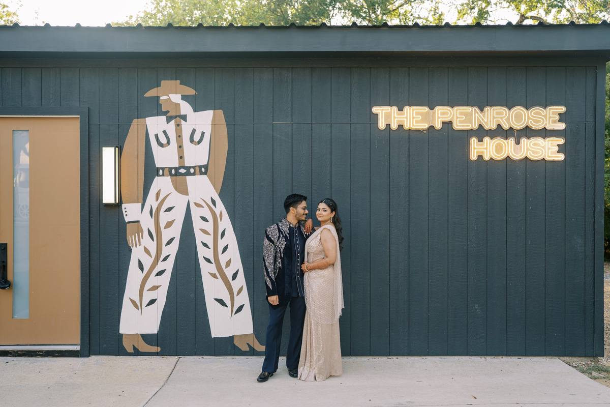 Couple posed in front of the Plus One Lounge exterior with The Penrose House neon sign and cowboy mural