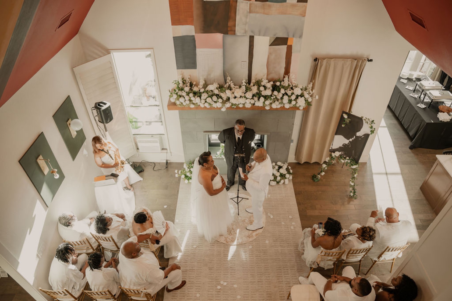 Aerial view of an indoor wedding ceremony with guests seated in rows facing the signature fireplace