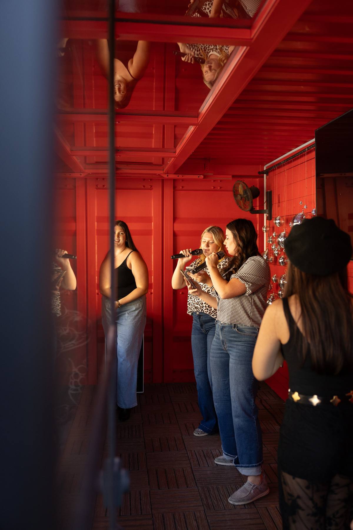 Friends singing karaoke in the red karaoke booth, The Penrose House