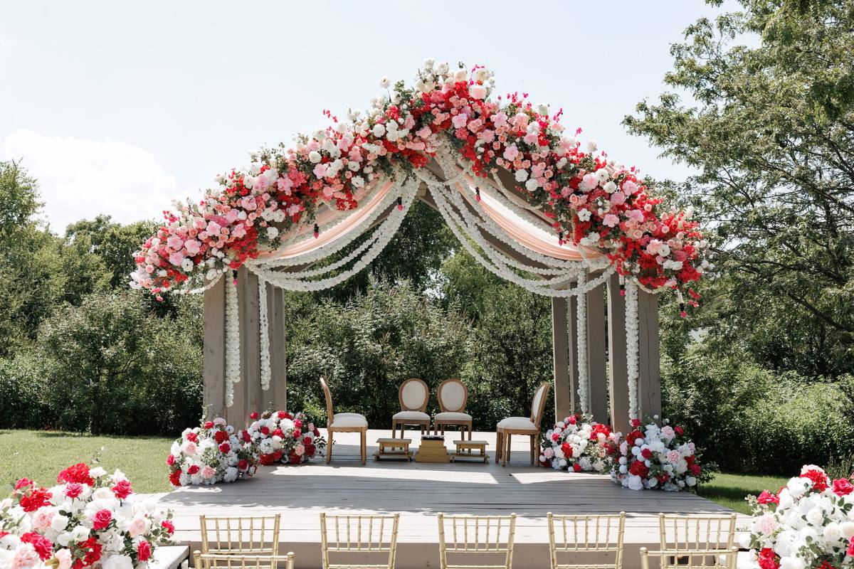 Mandap with red and pink florals and jasmine garlands on the ceremony deck, The Penrose House