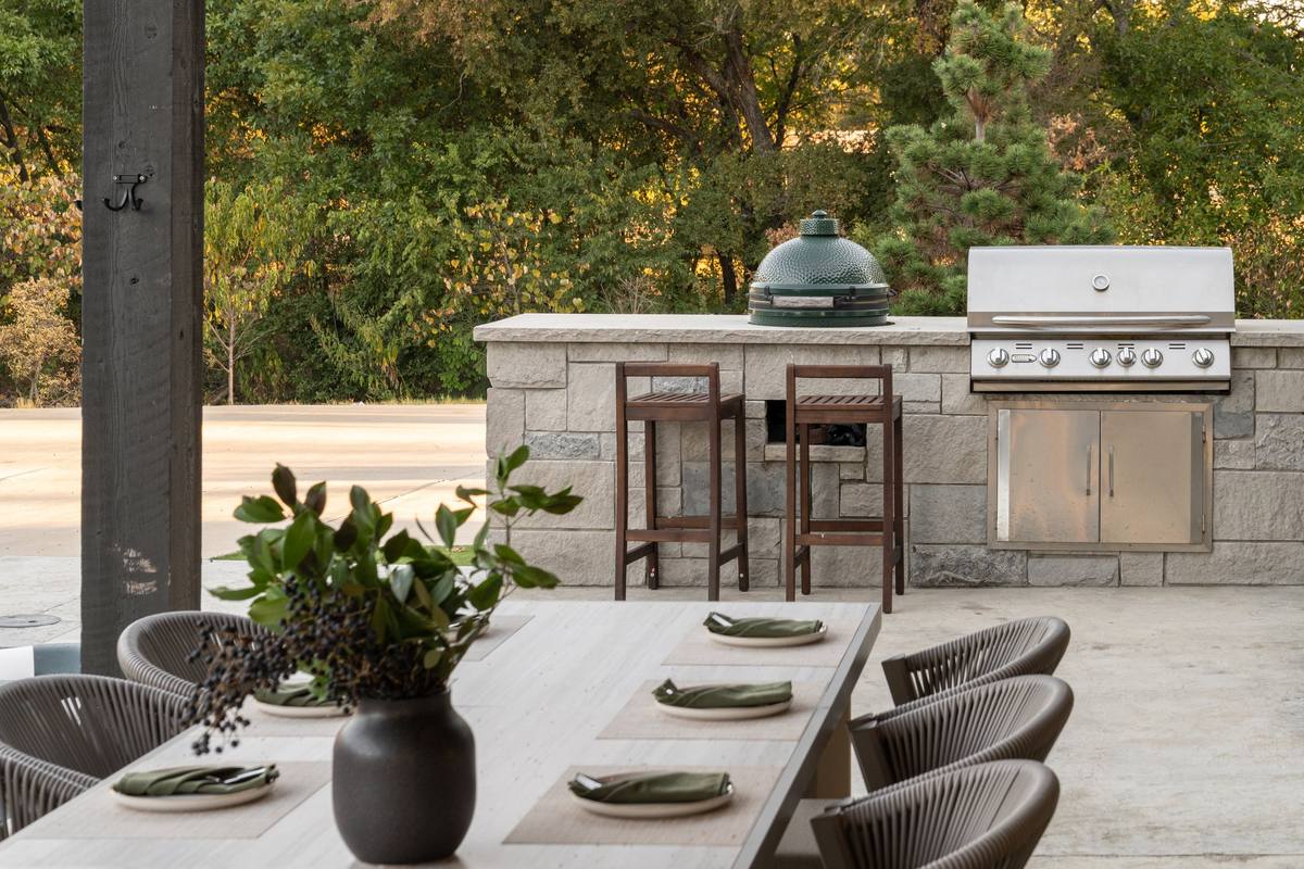 Outdoor kitchen with grill and bar seating beside the dining patio, The Penrose House