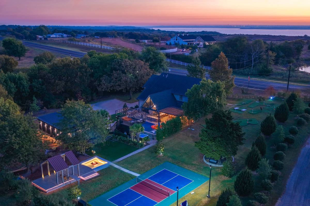 The Penrose House estate at twilight with landscape and court lighting, aerial view