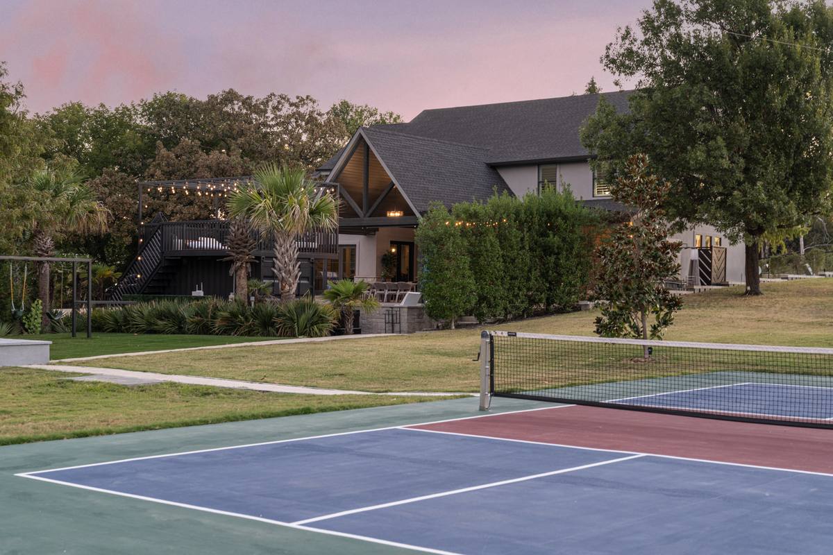 Lighted pickleball court at dusk with the house behind, The Penrose House