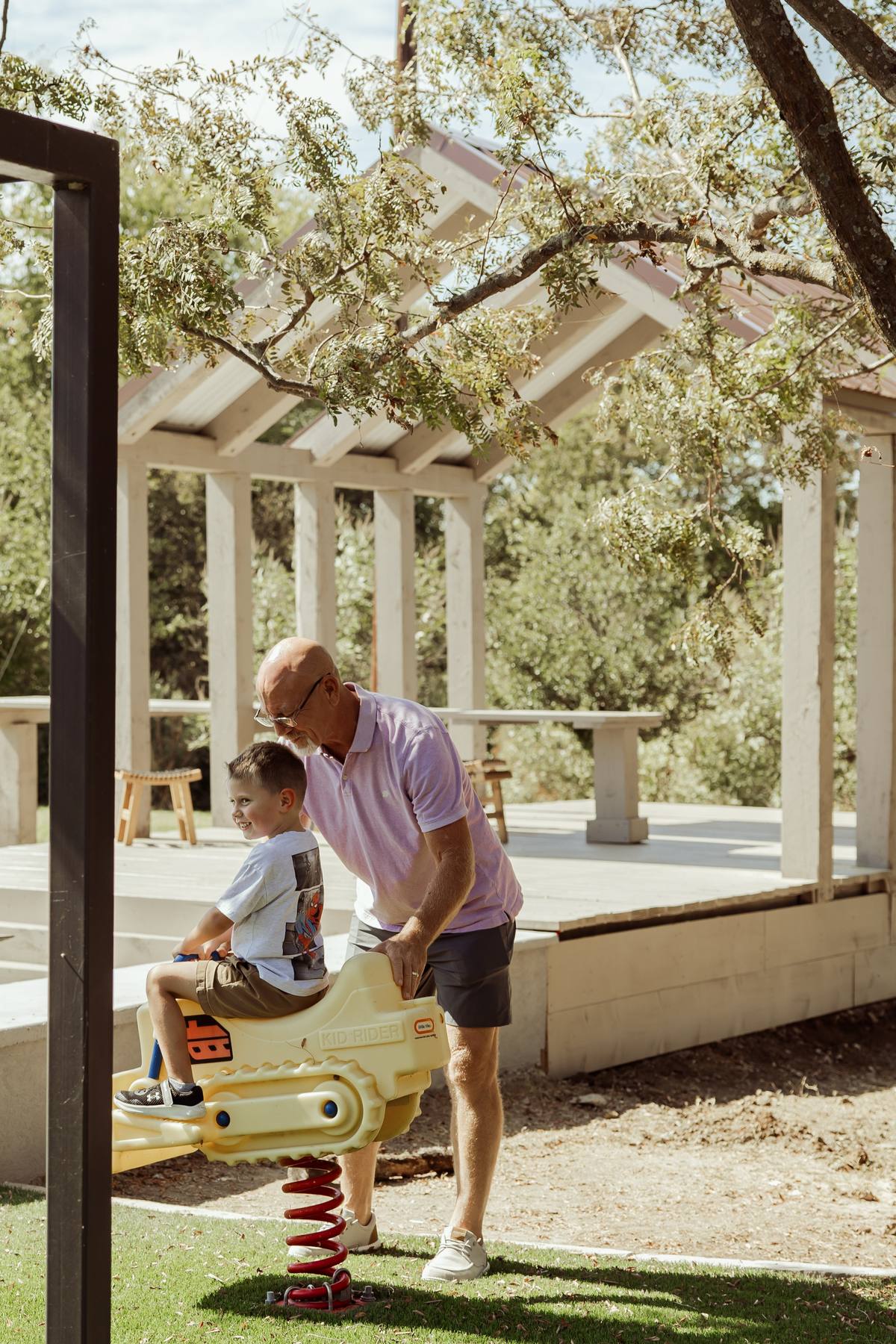Grandfather and grandson on the playground spring rider, The Penrose House