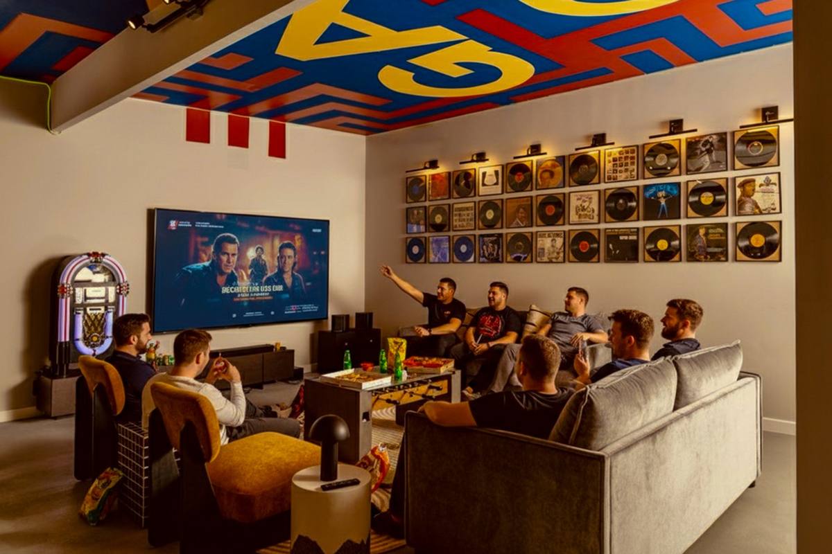 Guests watching a movie on the big screen in the Plus One Lounge, The Penrose House