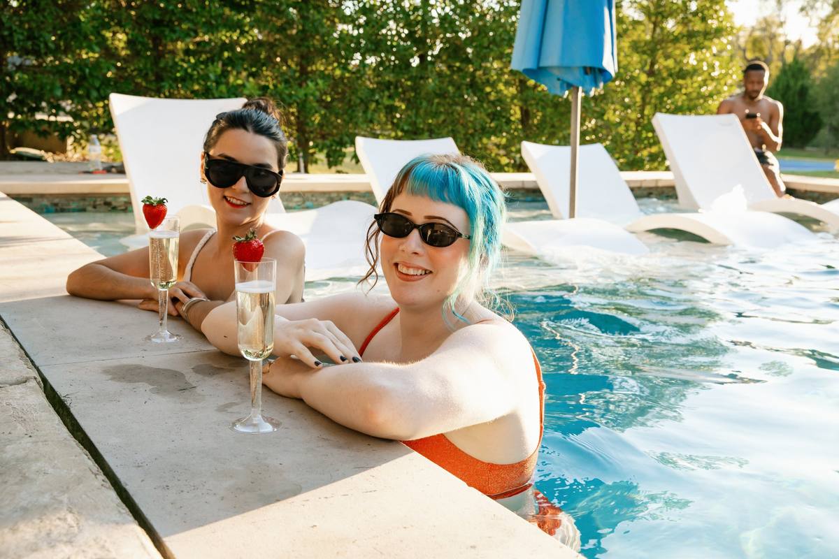Friends with champagne at the pool edge, The Penrose House
