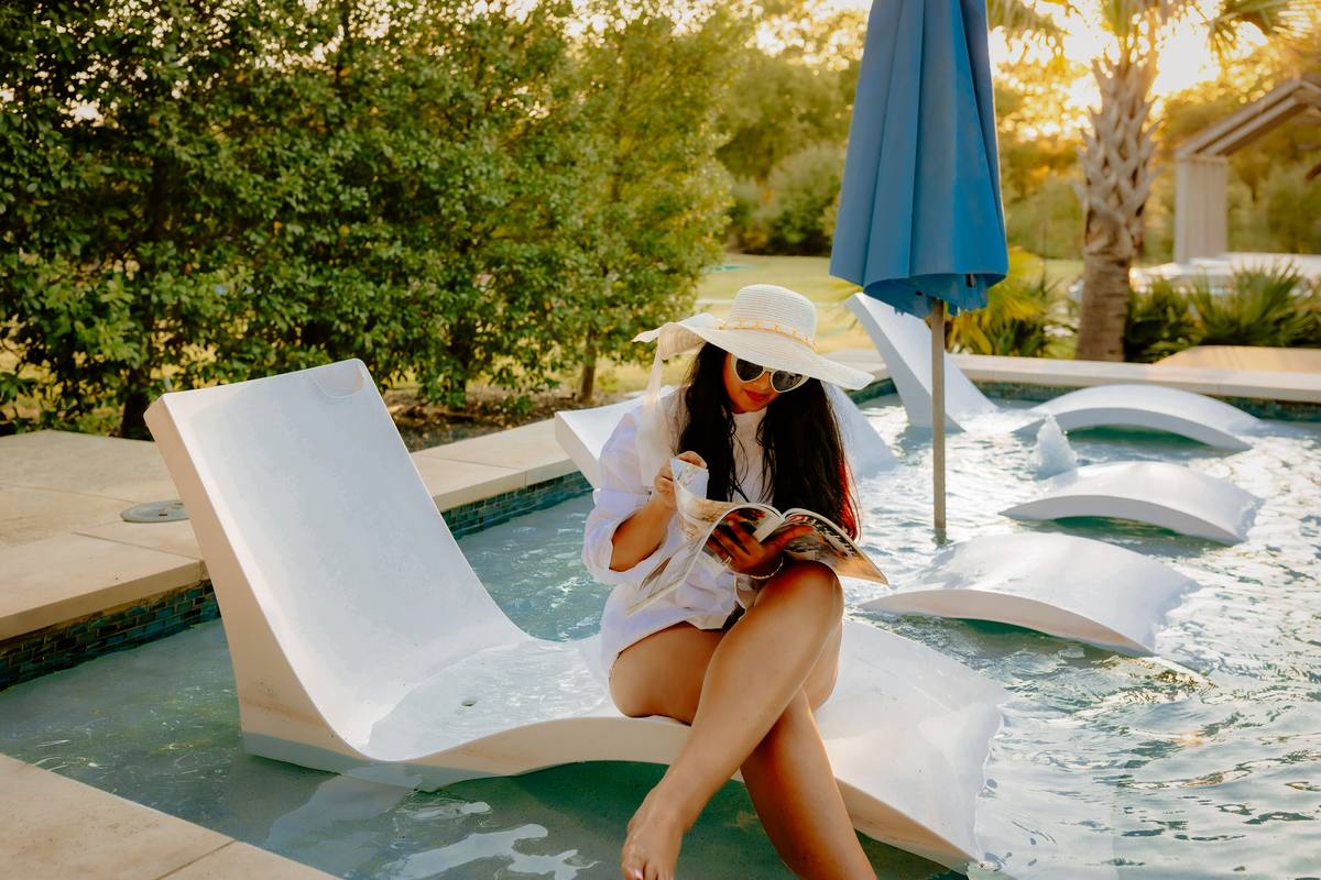 Guest reading on an in-pool lounger under an umbrella, The Penrose House