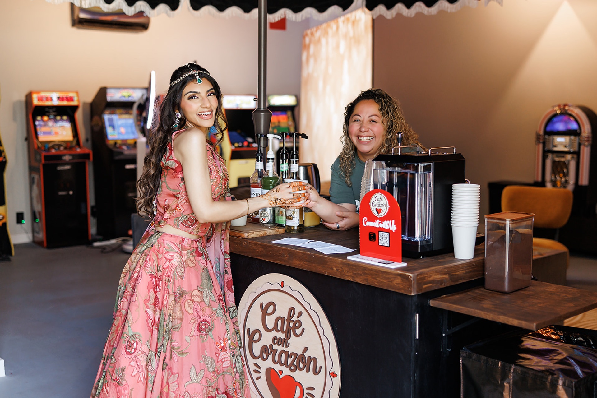 South Asian guest at the Café con Corazón cart being served by the barista, arcade in background