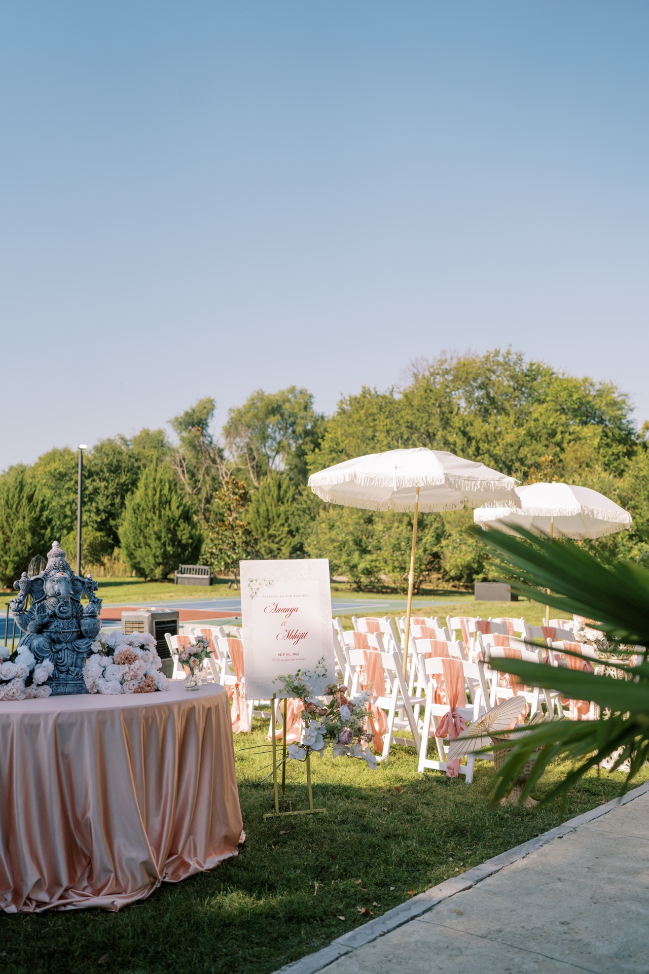 Outdoor South Asian wedding setup with Ganesh statue, peach floral canopy and welcome signage