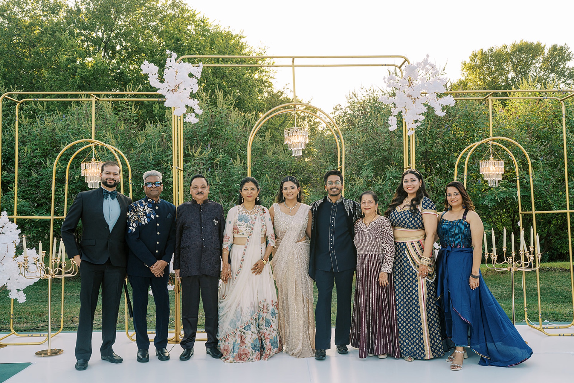 South Asian family portrait at the reception gold arch backdrop with crystal chandeliers