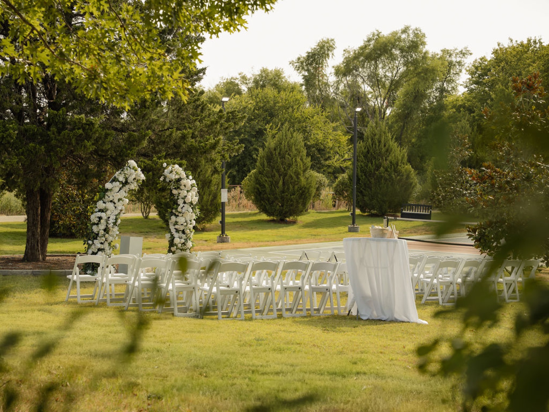 White floral ceremony arch with chairs on the open lawn at sunset, The Penrose House
