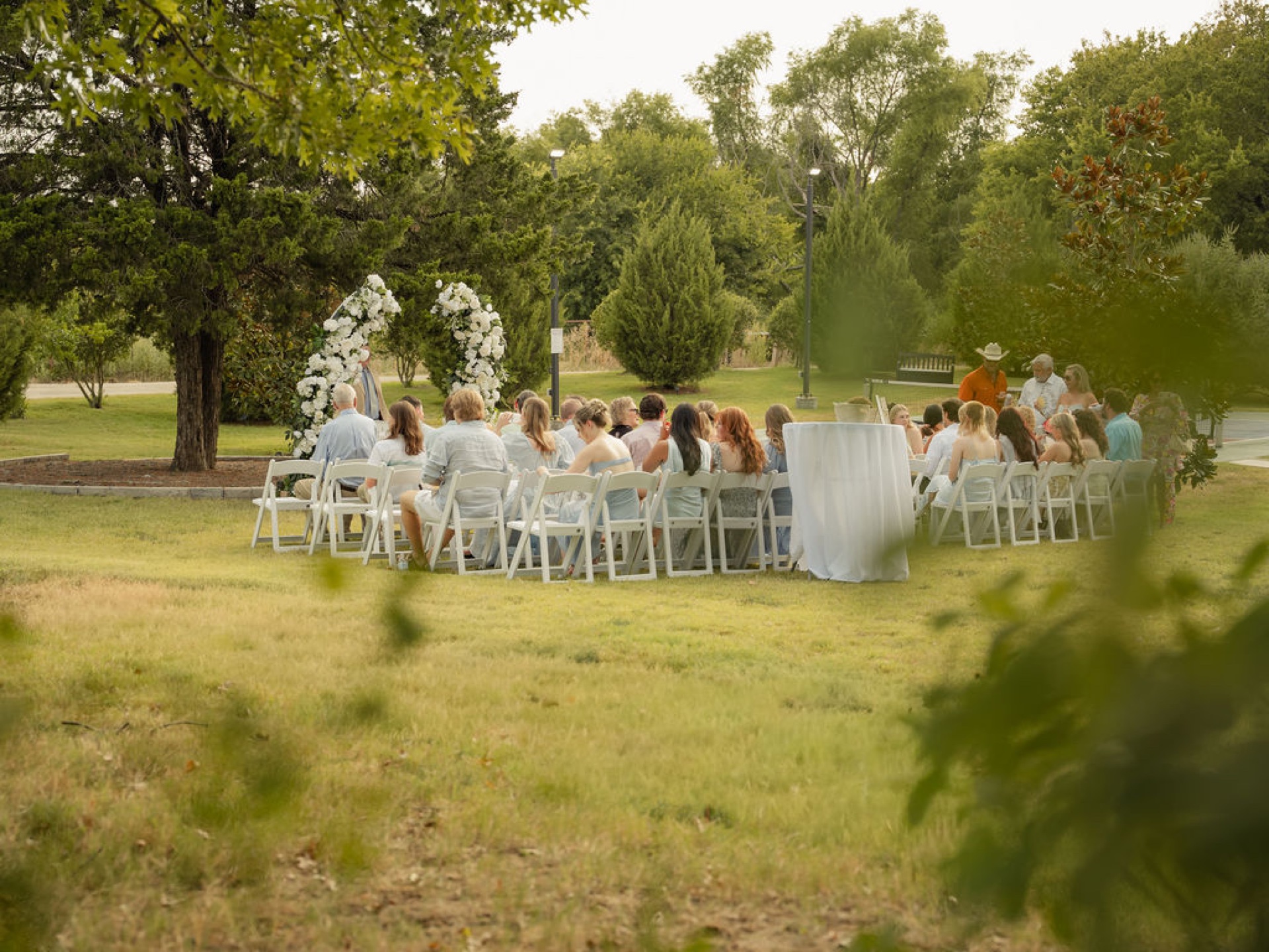 Guests seated at a long reception table beside the ceremony tree at The Penrose House