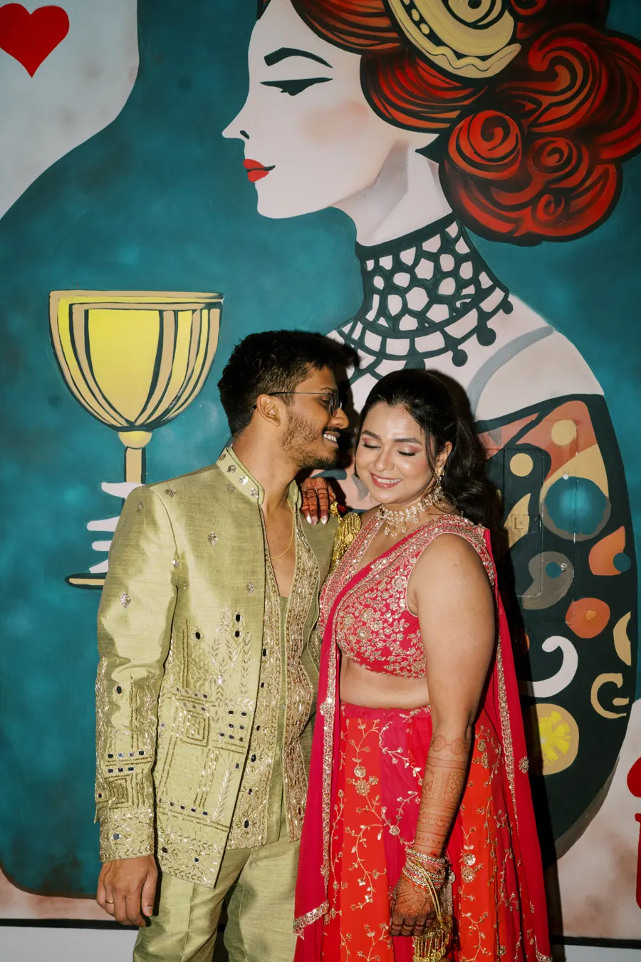 Indian couple in sangeet outfits in front of a painted mural wall at The Penrose House