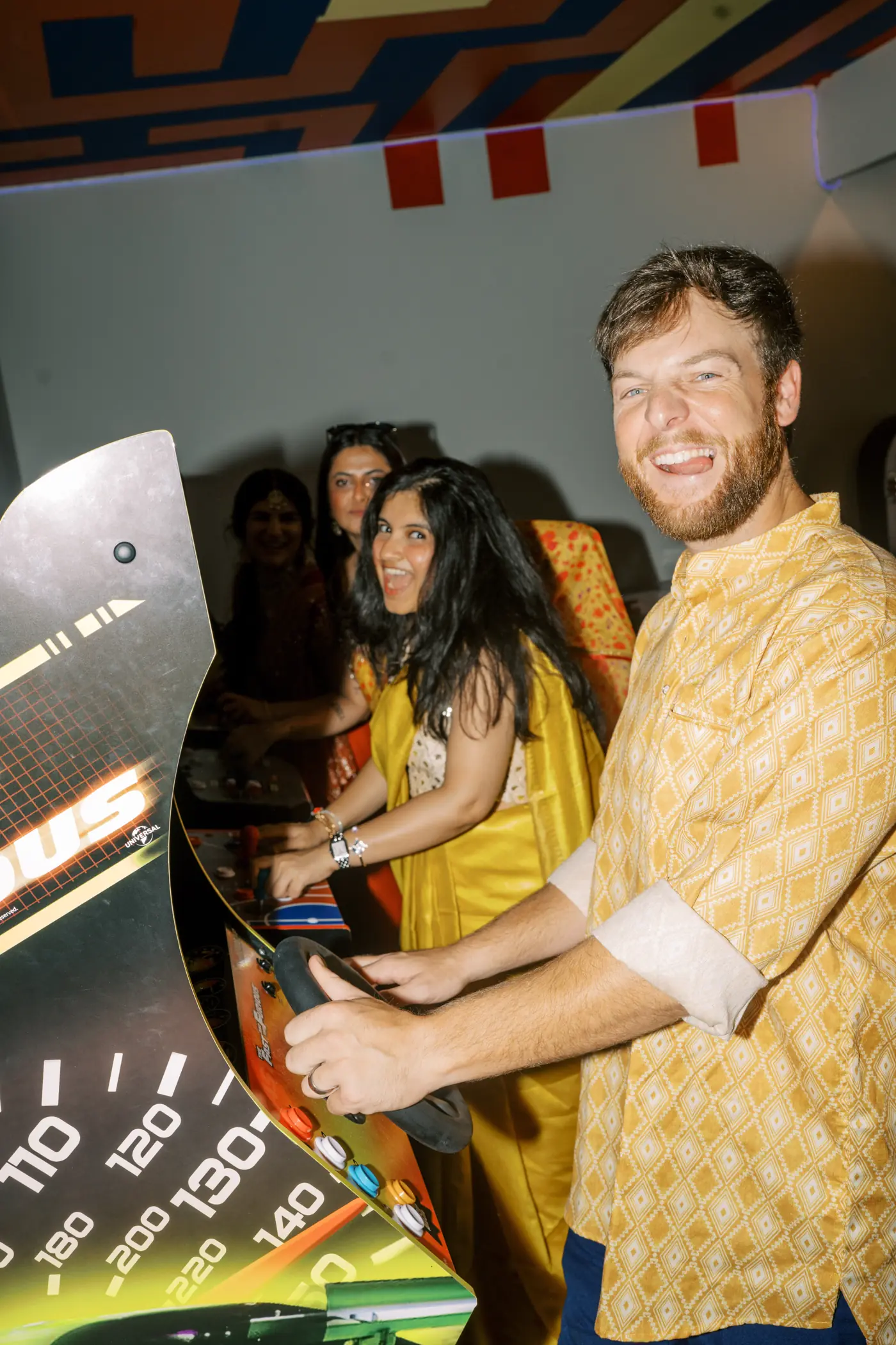 Wedding guests in Indian attire playing arcade racing games in the game room during a sangeet at The Penrose House